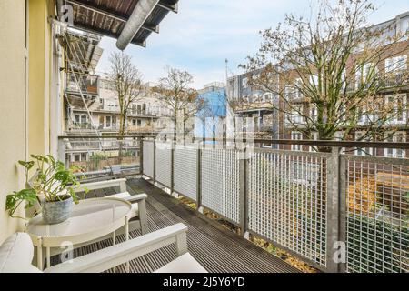 Chaises placées près d'une table avec plantes en pot et clôture en métal sur le balcon donnant sur les bâtiments situés dans la ville le jour d'été Banque D'Images