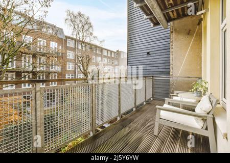 Chaises placées près d'une table avec plantes en pot et clôture en métal sur le balcon donnant sur les bâtiments situés dans la ville le jour d'été Banque D'Images