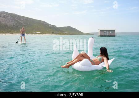 Couple sur cygne gonflable et paddle-board sur l'océan d'été Banque D'Images