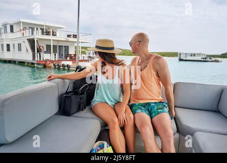 Couple se détendant sur le catamaran, regardant sur l'épaule à la péniche Banque D'Images