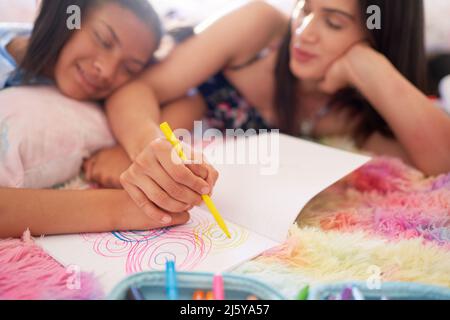 La mère et la fille dessinant ensemble des cercles dans un bloc-notes Banque D'Images