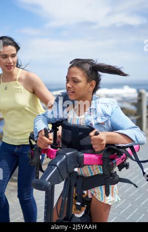 Mère et fille handicapée avec roller marchant sur la promenade Banque D'Images