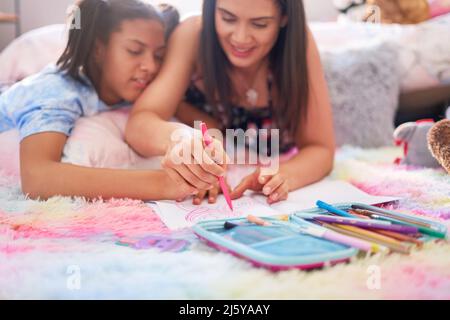 Mère et fille dessin avec marqueur dans un carnet sur un tapis Banque D'Images