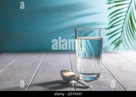 poudre de collagène matcha dans une cuillère et un verre d'eau, concept sain et anti-âge. Créatif Banque D'Images