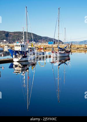 Les bateaux à voile se reflètent dans l'eau calme de Trondheim, en Norvège Banque D'Images