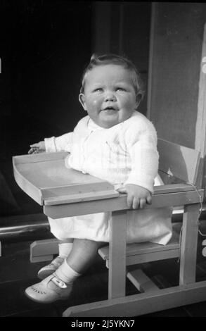 1960, historique, enfant en bas âge assis dans une chaise haute en bois, Angleterre, Royaume-Uni. Banque D'Images