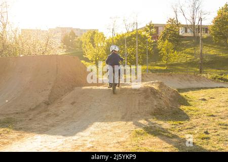 Enfant à vélo. Enfant sur un vélo à la piste de pompe. Enfant actif. Jour d'été ensoleillé. Banque D'Images