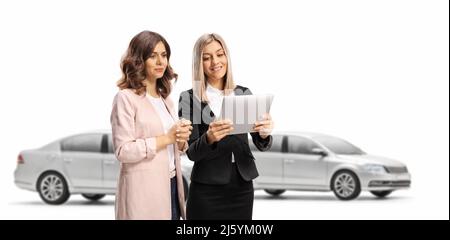 Femme d'affaires montrant une tablette à une jeune femme dans une salle d'exposition de voiture isolée sur fond blanc Banque D'Images