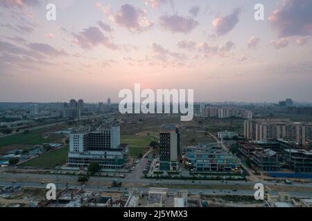 prise de vue aérienne au crépuscule montrant le centre commercial de 3 routes à gurgaon avec les feux allumés et la circulation se déplaçant sur la route très fréquentée en face et les chantiers de construction tous Banque D'Images