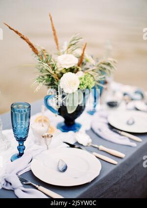 Dîner d'art sur la plage. Mariage bleu. Restauration. Bouquet de mariage avec fleurs tendres dans vase sur table, cadre élégant Banque D'Images