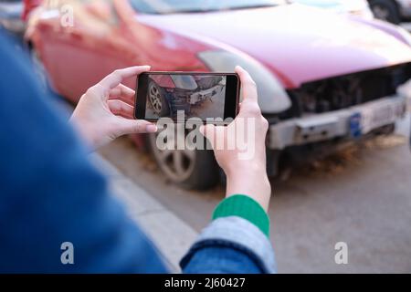 Agent d'assurance photographiant une voiture brisée sur un téléphone portable de près Banque D'Images