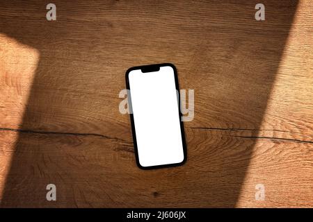 Smartphone avec écran tactile maquette blanc vierge sur table en bois de teck, vue de dessus Banque D'Images