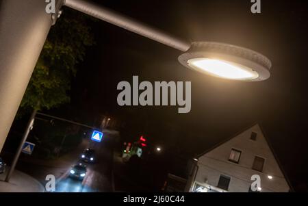 Heiningen, Allemagne. 26th avril 2022. Les voitures circulent sous un éclairage de rue dont la luminosité est contrôlée par l'intelligence artificielle. La nuit, l'éclairage de l'artère locale doit être ajusté au volume de la circulation, protégeant ainsi les insectes. Les animaux sont attirés par la lumière et meurent dans les luminaires ou le cercle devant eux jusqu'à ce qu'ils soient épuisés. Un système de caméra sera également utilisé pour compter les insectes. Credit: Stefan Puchner/dpa/Alay Live News Banque D'Images