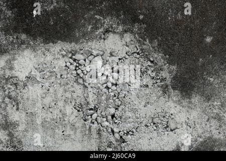 Mur de béton blanc et noir abîmé avec de petits morceaux de béton en forme de roche lâche tombant Banque D'Images