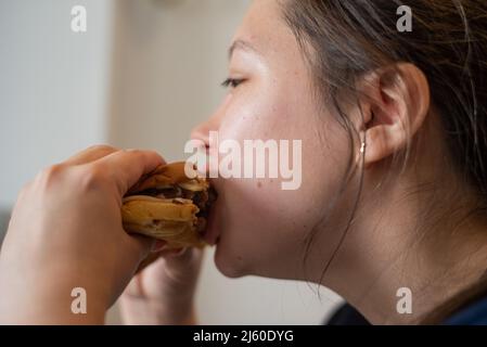 Une jeune femme latina mange des biscuits et de la crème glacée à la maison Banque D'Images