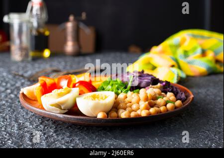 Salade - plat de saveur à base de tomates, concombres, chou rouge et persil, pois chiches servis avec des œufs durs et de la sauce Tahini Banque D'Images