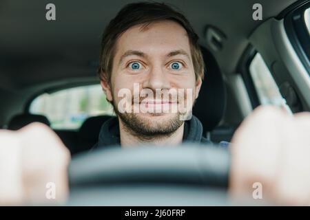 Gros plan du mendiant heureux et excités derrière le volant de sa première voiture. Banque D'Images