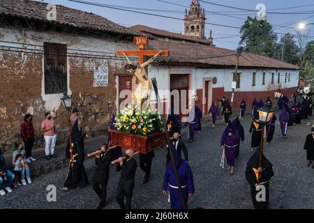 Les pénitents à capuchon catholiques romains portant des capirotes traditionnels portent une statue de Jésus-Christ lors d'une procession de silence le samedi Saint, 16 avril 2022 à Patzcuaro, Michoacan, Mexique. La petite ville indigène conserve les traditions de la domination coloniale espagnole, y compris la confraternité des pénitents pendant la semaine sainte. Banque D'Images