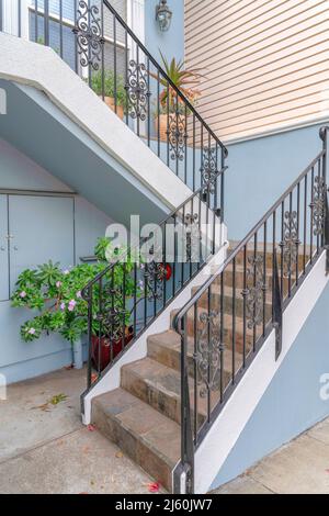 Escaliers à l'extérieur de la maison avec des plantes en pot, une main courante en fer forgé, et des marches en carreaux de pierre Banque D'Images