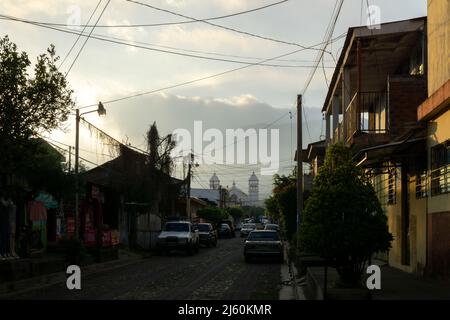 Juayua, El Salvador - 29 janvier 2022: Vue de la route vide avec des voitures garées dans la zone résidentielle de Juayua, El Salvador au coucher du soleil Banque D'Images