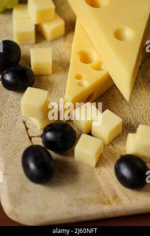 Fromage coupé avec des fruits.fromage Mazdar, cubes de fromage gouda et raisins noirs.fromage aux raisins baies sur bois background.milk de graisse et produits laitiers. Banque D'Images