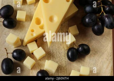 Fromage coupé avec des fruits.triangles de fromage Mazdar, cubes de fromage gouda et raisins noirs.fromage aux raisins baies sur bois background.milk de graisse et lait Banque D'Images