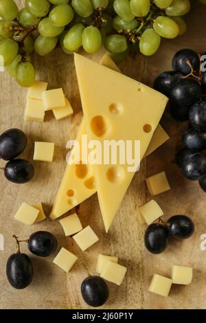 Fromage coupé avec des fruits.triangles de fromage Mazdar, cubes de fromage gouda et raisins noirs et verts.fromage aux raisins baies sur bois background.milk de graisse Banque D'Images