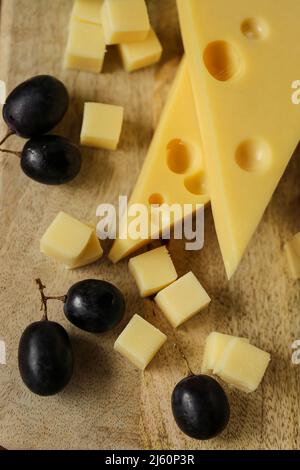 Fromage coupé avec des fruits.triangles de fromage Mazdar, cubes de fromage gouda et raisins noirs.fromage avec des raisins sur fond de bois Banque D'Images