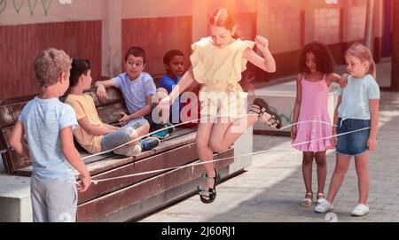 Bonne petite fille saut de jeu par le groupe de caoutchouc avec des amis Banque D'Images