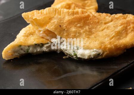 Cuisine orientale ouzbek tatar, chebureau au fromage suluguni un tableau noir. Chebureau - tarte frite. Plat traditionnel turc et mongol Banque D'Images