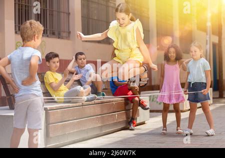 Bonne petite fille saut de jeu par le groupe de caoutchouc avec des amis Banque D'Images