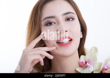 Belle jeune femme chinoise souriante dans les orchidées de papillons, sur fond blanc - photo de stock Banque D'Images