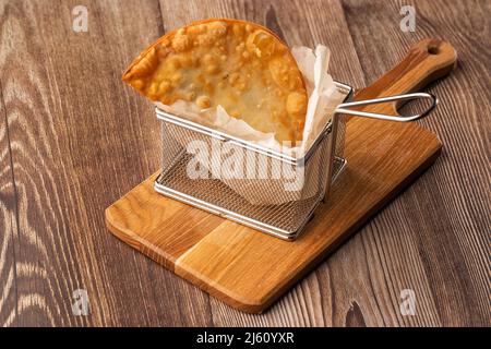 Cuisine ouzbek orientale tatar, chebureau sur une planche de bois. Chebureau - tarte frite à la viande. Plat traditionnel de turc et mongol, pasties empanada Banque D'Images