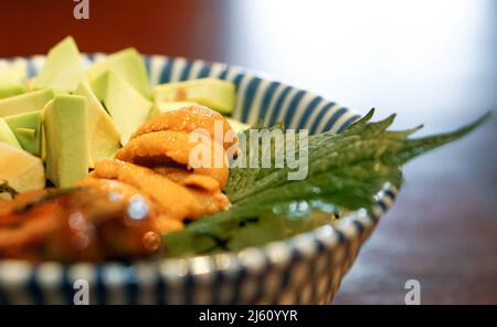 Bol à riz mélangé pour aliments frais de qualité supérieure. Riz japonais avec Uni, foie gras et avocat décoré de feuilles de shiso vertes. Vue latérale Banque D'Images