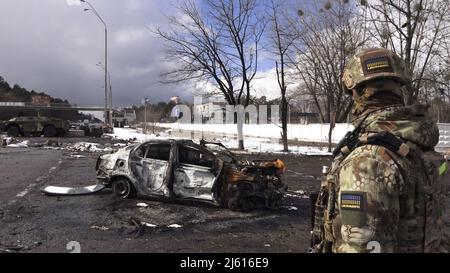 BROVARY, UKRAINE 08 mars. Un membre de l'armée ukrainienne regarde l'épave d'une voiture qui a été détruite lors d'une bataille avec des soldats russes sous couvert à un point de contrôle près de la ville de Brovary, à l'extérieur de Kiev, alors que l'invasion de l'Ukraine par la Russie se poursuit le 08 mars 2022 à Brovary, en Ukraine. La Russie a commencé une invasion militaire de l'Ukraine après que le Parlement russe ait approuvé des traités avec deux régions sécessionnistes de l'est de l'Ukraine. C'est le plus grand conflit militaire en Europe depuis la Seconde Guerre mondiale Banque D'Images