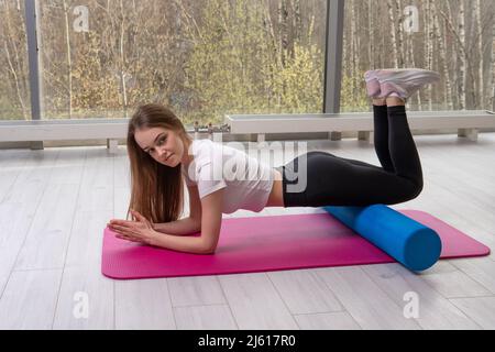 Roller repose le mfr sur la fille le tapis rouge de fitness mfr sportswear, pour l'exercice gai pour le sport et l'entraînement jeune, fille sportive. Pied de position de planche Banque D'Images