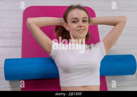 La fille est de forme physique mfr rouleau sur tapis rouge mfr sportswear, de la forme gaie pour l'exercice de jeunes, pilote sportive. Copie de gymnastique Banque D'Images