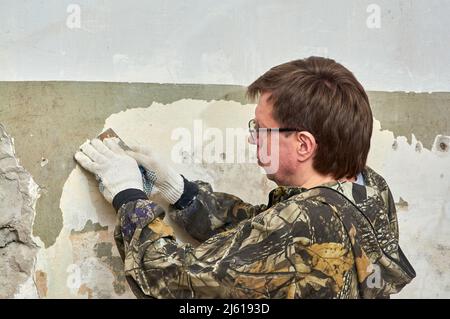 enlever la peinture du mur à l'aide d'un grattoir, réparer la pièce Banque D'Images