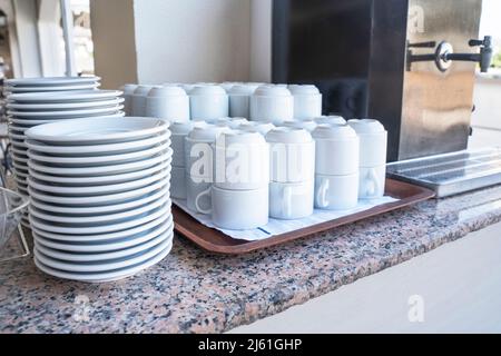 Un buffet de plats blancs et de tasses est disponible sur la table. Banque D'Images