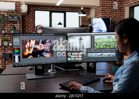 Éditeur de films professionnel de la société créative installé sur une station de travail à plusieurs moniteurs lors du montage de cadres de film. Vidéaste expert améliorant la qualité vidéo à l'aide de logiciels spécialisés. Banque D'Images