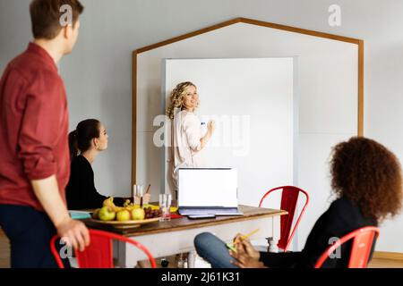 Femme d'affaires souriante expliquant la stratégie d'entreprise à ses collègues dans la salle de projet au bureau Banque D'Images