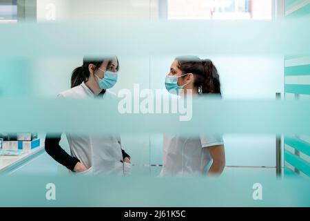 Les infirmières dans les masques protecteurs du visage discutant à la clinique maxillofacial Banque D'Images