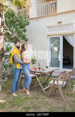Couple heureux debout près d'une table dans le jardin arrière Banque D'Images