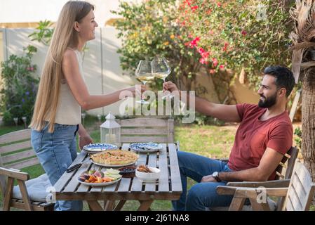 Couple de brunissage avec des lunettes de vin en prenant le petit déjeuner dans le jardin Banque D'Images