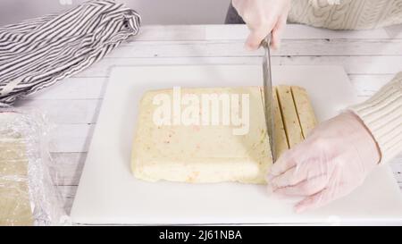 Étape par étape. Coupe de fudge de canne à sucre fait maison sur un tableau de découpe blanc. Banque D'Images