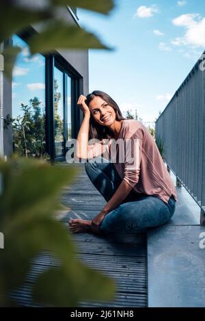 Belle femme heureuse assise sur le balcon Banque D'Images