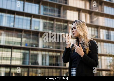 Femme d'affaires envoyant la messagerie vocale via un smartphone Banque D'Images