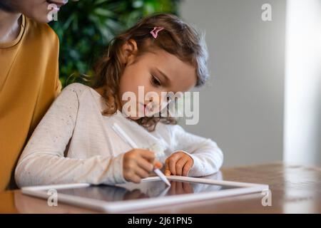 Jolie fille écrivant sur un Tablet PC avec un stylo numérique à la maison Banque D'Images
