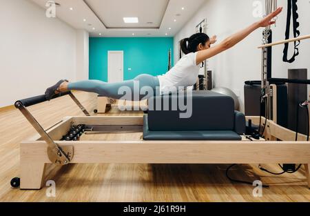 Femme pratiquant des pilates allongé sur un reformeur en studio Banque D'Images