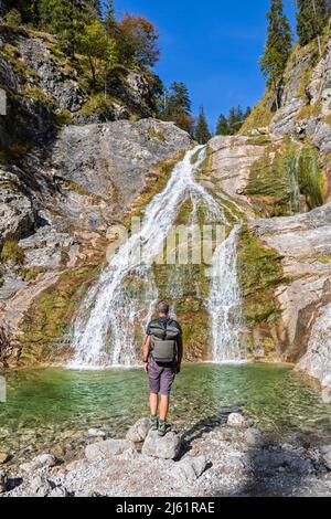 Randonneur mâle admirant la chute d'eau de Glasbach à Prealps bavarois Banque D'Images